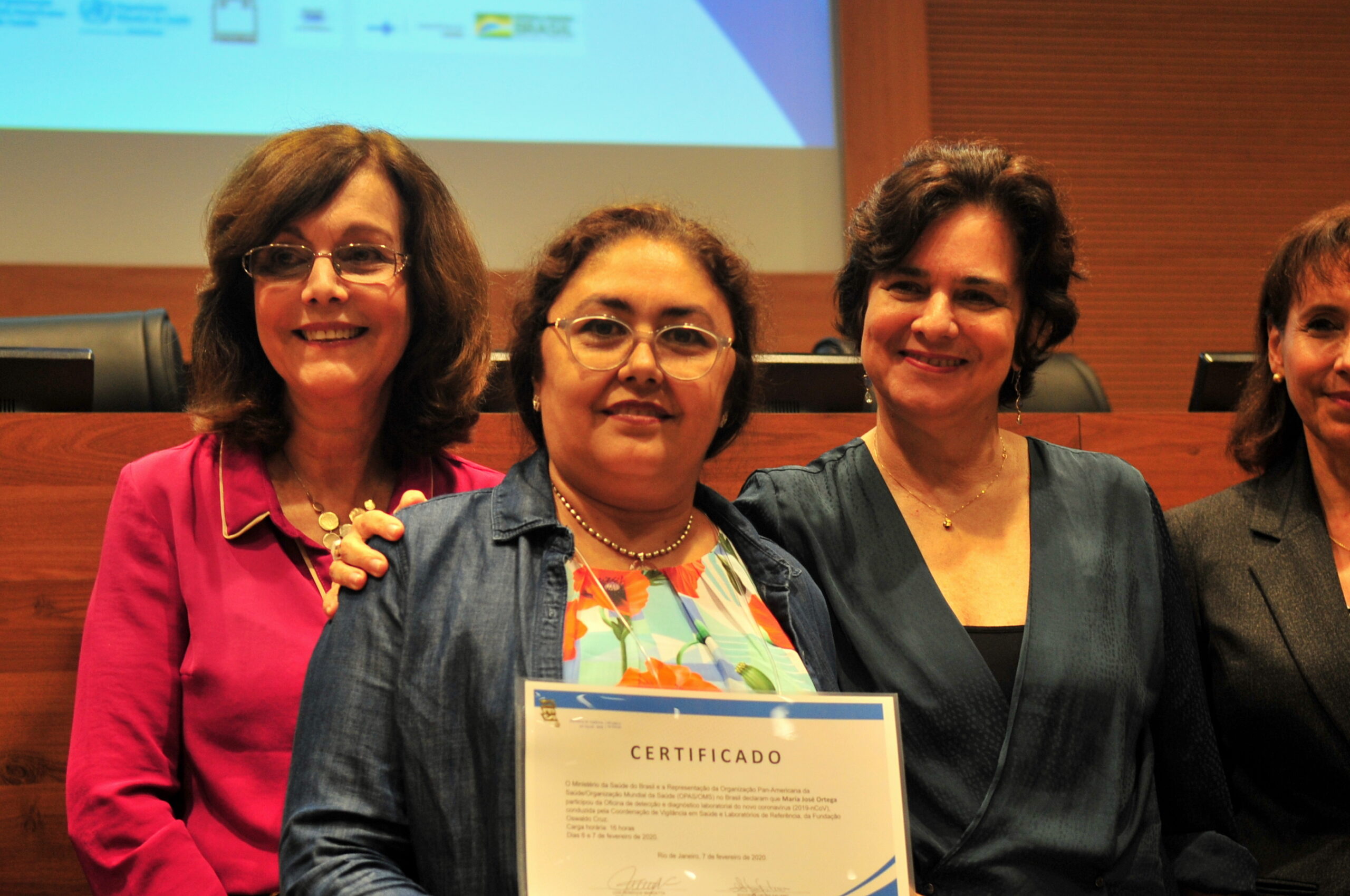 Maria José Ortega recebe certificado de participação na oficina de capacitação de laboratórios públicos latino-americanos para o diagnóstico do novo coronavírus, organizada pelo Ministério da Saúde e pela Organização Panamericana da Saúde (OPAS) e realizada na Fiocruz. Da esquerda para a direita: Marilda Siqueira, chefe do Laboratório de Vírus Respiratórios e Sarampo/Instituto Oswaldo Cruz/Fiocruz; Maria José Ortega; Nísia Trindade Lima, presidente da Fiocruz; e Socorro Gross, Organização Panamericana da Saúde. Rio de Janeiro, 6-7 de fevereiro de 2020. Foto: Pedro Paulo. Acervo CCS/Fiocruz.